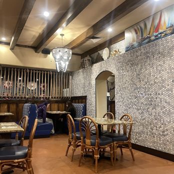 Mariscos Altamar - a dining area with tables and chairs - Interior of a restaurant with wooden ceiling beams, a chandelier, mosaic wall, and dining tables with chairs, with two people seated in the background. - Seafood Near Me - Los Lunas, New Mexico