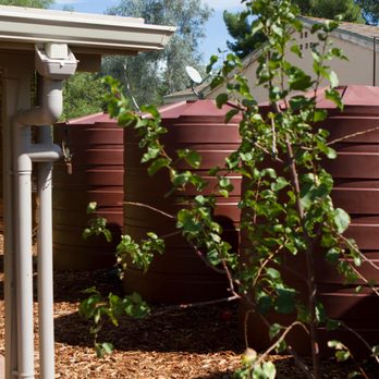EcoSense Sustainable Landscapes - a wooden bench in front of a water tank - Landscaping Near Me - Tucson, Arizona EcoSense Sustainable Landscapes - a wooden bench in front of a water tank - Landscaping Near Me - Tucson, Arizona