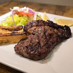 Premium ribeye steak with lemon potatoes and greek salad