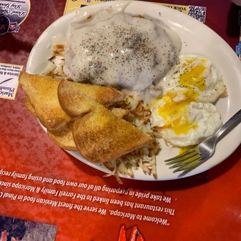Headquarters Cafe - Country/chicken Fried Steak - A breakfast plate featuring fried eggs, hash browns topped with gravy and pepper, and toasted bread slices, served on a white dish. - American Near Me - Maricopa, Arizona