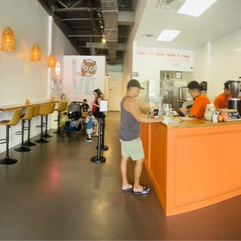 Doughfee - A donut and coffee shop interior featuring a counter with staff, seating area with bar stools, and customers ordering or waiting. - Coffee & Tea Near Me - Jacksonville, Florida