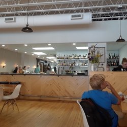 Leader - View of bar counter.  Clean tables set with silverware wrapped in white linens.
