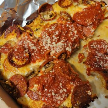 Futuro - A close-up of a pizza slice featuring toppings such as pepperoni, sausage, mushrooms, and melted cheese. The pizza is placed on aluminum foil inside a cardboard pizza box, showing a variety of toppings and a layer of tomato sauce beneath the cheese. - Pizza Near Me - Indianapolis, Indiana