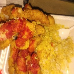 Sweet and Sour Chicken - Fried chicken pieces with red sauce are placed next to yellow rice on a foam plate, with a plastic spoon visible.