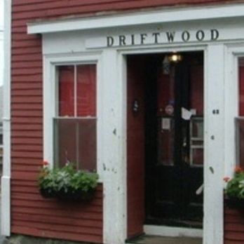 Driftwood - the entrance to driftwood - The image depicts the exterior of Driftwood, a small business with red horizontal siding, white trim, and flower boxes on either side of the entrance. - American Near Me - Marblehead, Massachusetts