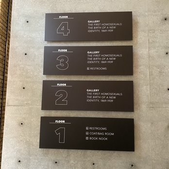 Wrightwood 659 - Four black signs mounted on a concrete wall provide information about the floors and exhibits at Wrightwood 659 in Chicago. The signs list floors 4, 3, 2, and 1, with details about the galleries and amenities such as restrooms, coat/bag room, and book nook. The signage is minimalistic and organized, with white text on a black background, indicating the layout of the exhibition space for architecture and socially engaged art. - Art Galleries Near Me - Chicago, Illinois