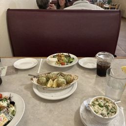 Stuffed Mushrooms - A restaurant table features dishes like stuffed mushrooms, salad, and soup, with diners and holiday decor visible in the background.