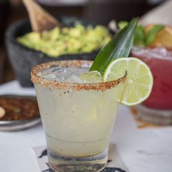 A refreshing margarita with a chili-salt rim, paired with fresh guacamole for a perfect meal.