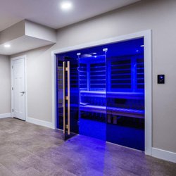 Spas Unlimited - Houston - Custom Indoor Sauna with a blue light. Sauna is in a room with an additional door.