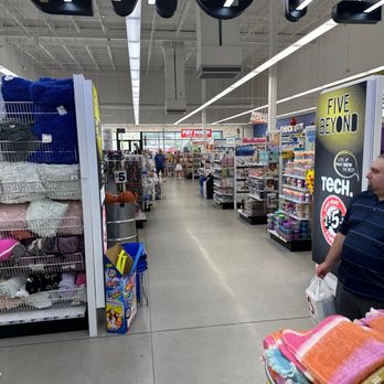 Five Below - A wide aisle inside a Five Below store shows shelves stocked with various products, shoppers browsing, and store signage. - Department Stores Near Me - Saint Johns, Florida