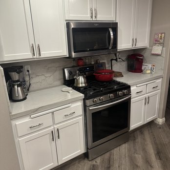 Granite King - a kitchen with white cabinets and stainless steel appliances - General Contractors Near Me