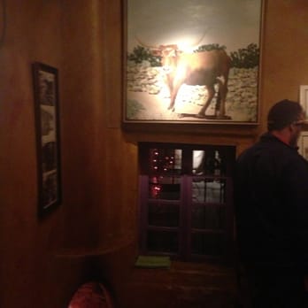 The Shed - Love the entry with the little fireplace & big cow picture - New Mexican Cuisine Near Me - Santa Fe, New Mexico