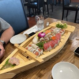 Assortment of rolls including Spicy Tuna, Rainbow roll, Eel roll, and yellowtail sashimi.