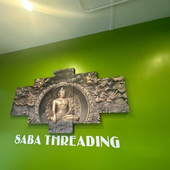 Saba Threading - A multi-panel Buddha statue is displayed on a bright green wall with the text "SABA THREADING" underneath, indicating a business location. - Threading Services Near Me - Boston, Massachusetts