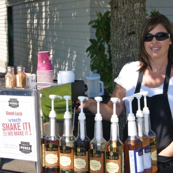 Pacific Perks Mobile Café - a woman standing behind a table with bottles of liquor - Party & Event Planning Near Me Pacific Perks Mobile Café - a woman standing behind a table with bottles of liquor - Party & Event Planning Near Me