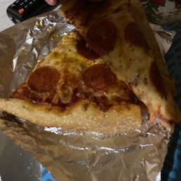 My cold soggy pizza from Mary Deli 0 - A slice of pepperoni pizza with melted cheese and pepperoni slices is being lifted from a foil-lined pizza box.