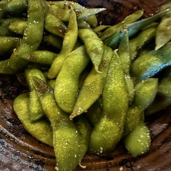Akira - Cooked edamame beans are shown in a wooden bowl, with a shiny, slightly salted appearance. - Sushi Bars Near Me - Eugene, Oregon