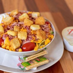 A half chef salad with side of ranch dressing and crackers.