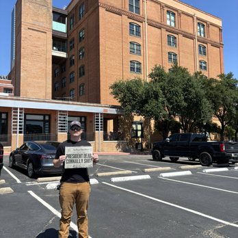 JFK Memorial - Parking lot outside memorial, holding a newspaper from the day after JFK was shot. - Museums Near Me - Fort Worth, Texas