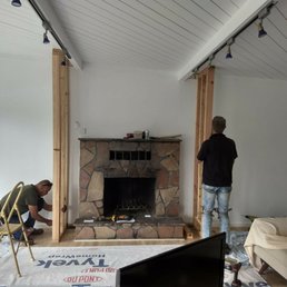 Before old stone fireplace.
