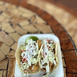 FISH TACOS: LIGHTLY BARTERED FRIED FISH, CABBAGE, PICO DE GALO, SPECIAL FISH CREAM, LEMON WEDGE & CORN TORTILLA (SINGLE) | $5.5