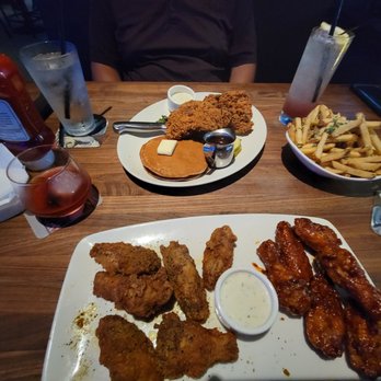 Yard House - Dinner time = Accross the table: Nashville Chicken + Pancakes In front of me: Traditional Wings, bbq & lemon pepper Shared Truffle Fries - New American Near Me - Orlando, Florida