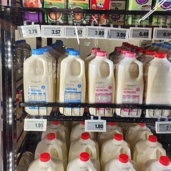 Amazon Fresh - Refrigerated shelves at Amazon Fresh grocery store hold various milk bottles, including low-fat, fat-free, and whole milk, with price tags visible. - Grocery Near Me - Fullerton, California
