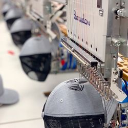 Custom hats being embroidered with high-quality precision on our assembly line.