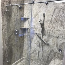 True North Kitchen and Bath - Gorgeous Valencia Granite shower system with modern barn style glass doors, and brushed nickel fixtures.