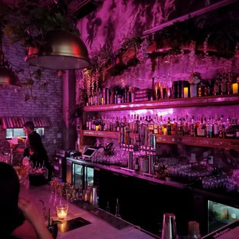 DOM'S - a dimly lit bar with bottles of alcohol - Cocktail Bars Near Me - Miami, Florida