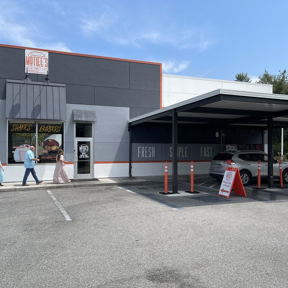 The side entrance and drive-through at Mottlee's, which has some outdoor tables at the left.
