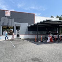 The side entrance and drive-through at Mottlee's, which has some outdoor tables at the left.