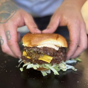 Doinks Burger Joint - a man holding a hamburger - Burgers Near Me - Cleveland, Ohio
