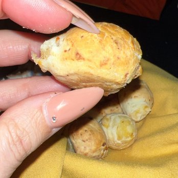 Frix's Fire Grill - A person holds a cooked mushroom with a yellowish cap, with several similar mushrooms on a yellow cloth in the background. - Latin American Near Me - Chester, Maryland