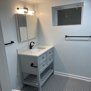 SR Home Improvements - Basement Bathroom - Bathroom with a vanity, mirror, black fixtures, and a small window, with hexagonal floor tiles and white walls. - Painters Near Me - Burke, Virginia