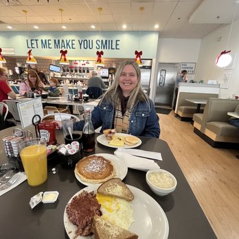 Eggs Up Grill - a woman sitting at a table with breakfast - Breakfast & Brunch Near Me - Hendersonville, North Carolina