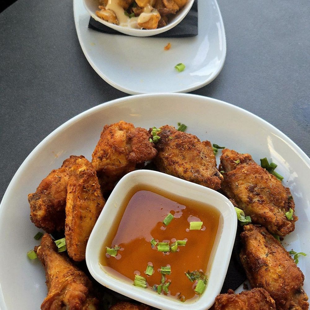 Lavender Rooftop Kitchen & Bar - Alita De Pollo served with spicy hot honey. Crispy potatoes are in the background. - Wine Bars Near Me - Savannah, Georgia