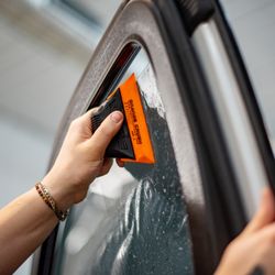 Pristine Auto Spa - Using a soft orange card to tack the window tint to the window
