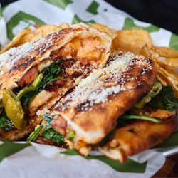 Uccello's - Downtown - Close-up of a toasted flatbread sandwich showing a cross-section of chicken, gouda, and spinach...