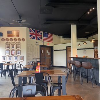 Casper Brewing Company - Seating area - A brewery interior features wooden tables, metal chairs, and patriotic flags on the wall, including the American, Scottish, and British flags. - Breweries Near Me - Bloomington, Illinois
