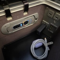 British Airways - BA284 SFO-LHR - storage cubby next to seat, with IFE remote & charging