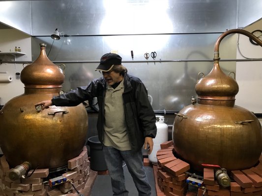 Photo of Pacific Distillery - Woodinville, WA, US. a man standing in front of two copper pots