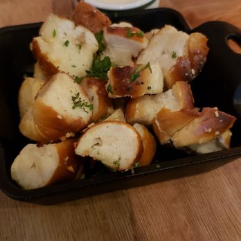 Thomas Murphy's Pub - Pretzel bites - A serving of pretzel bites, garnished with chopped herbs, is presented in a black tray on a wooden table. In the background, there is a small bowl of dipping sauce and a QR code on a piece of paper. The setting appears to be a casual dining environment, likely at Thomas Murphy's Pub in Gloucester City, NJ. - Pubs Near Me - Gloucester City, New Jersey