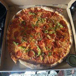 Pizza with pepperoni and green peppers with a side of pesto