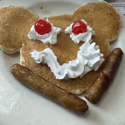 Maxim's Restaurant & Lounge - Mickey Mouse pancake with whipped cream and cherries and a side of sausage links