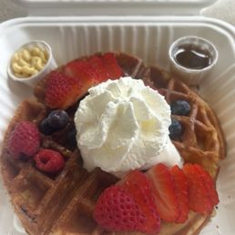 Mixed berry waffles airy coconut cream on the side.