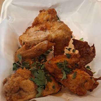Lan Viet - A serving of fried chicken pieces garnished with chopped herbs, presented in a white takeout container with parchment paper lining. - Vietnamese Near Me - Dublin, Ohio