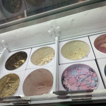 Baskin-Robbins - A variety of ice cream flavors are visible in open containers within a freezer at Baskin-Robbins in Mesa, AZ. The containers hold different colors and textures of ice cream, including chocolate, vanilla, and pink and blue swirled flavors. The freezer has a glass top with a white, textured surface around it, and the background shows part of the store interior with additional ice cream containers. - Ice Cream & Frozen Yogurt Near Me - Mesa, Arizona