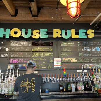 House Rules - a man standing in front of a bar - Tabletop Games Near Me - Grand Rapids, Michigan