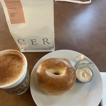 Concord Point Coffee - Latte with some cinnamon. Plain Bagel  Featuring the coffee bean used for the latte. - Cafes Near Me - Havre de Grace, Maryland